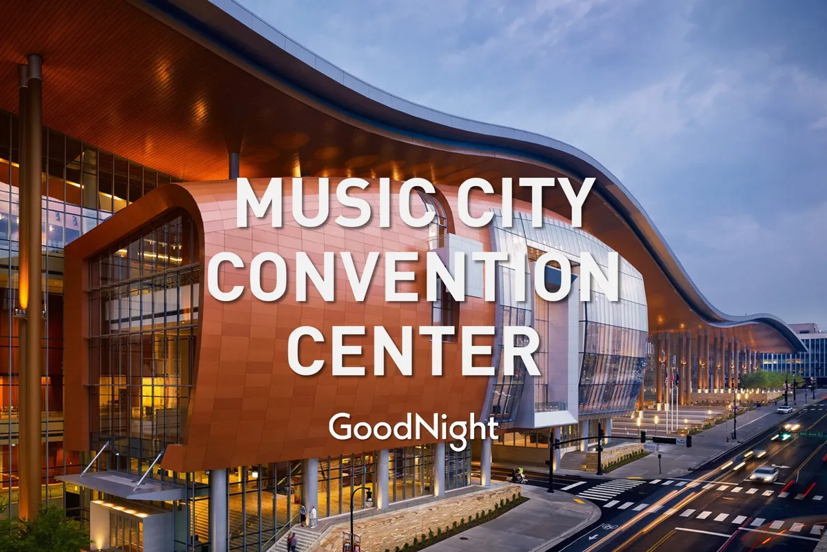 This image showcases the striking curved architecture and illuminated signage of the Music City Convention Center, with people visible outside. The large glass windows and bustling exterior convey a sense of activity and importance, capturing the central hub for business events and conferences in Nashville.